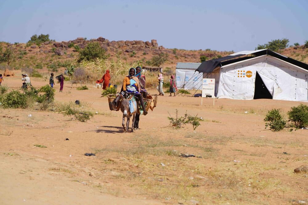 Des femmes refugiées transportant de l'eau à bords des ânes dans forage à coté d'un espace sur implanté par UNFPA